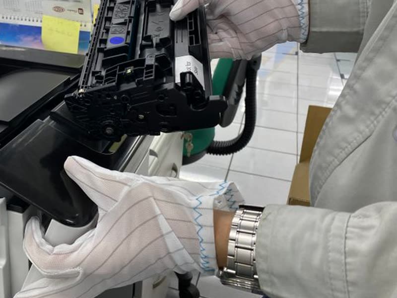 Manos con guantes retirando el cartucho de tóner de una impresora